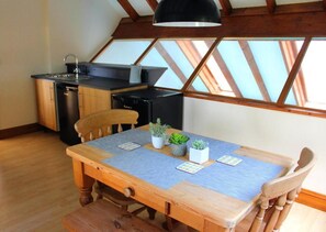 A compact kitchen with a dining table, chairs, and a ceiling fan. - 2-bed - Sleeps 4 - Free Parking & Ev Charging (Wadebridge)