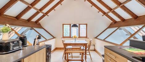 Una cocina con una mesa de madera, dos ventanas y un tragaluz.