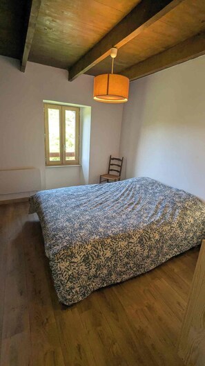 A bedroom with a bed, a window, a chair, and a hanging light fixture. - A vacation rental for 10 people, perfect for swimming, biking, and rock climbing. Pets are allowed. (Saint-Maurice-en-Chalencon)