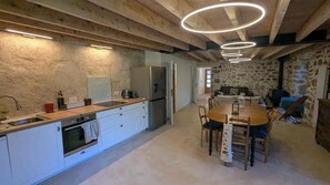 A modern kitchen with a central island, wooden ceiling beams, and a dining area with a round table and chairs. - A vacation rental for 10 people, perfect for swimming, biking, and rock climbing. Pets are allowed. (Saint-Maurice-en-Chalencon)