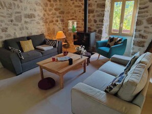 Un salon chaleureux avec un mur en pierre, une cheminée, un canapé, une table basse et une fenêtre.