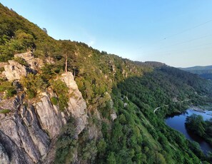 A mountainous landscape with a river, rocky cliffs, and dense forest. - A vacation rental for 10 people, perfect for swimming, biking, and rock climbing. Pets are allowed. (Saint-Maurice-en-Chalencon)