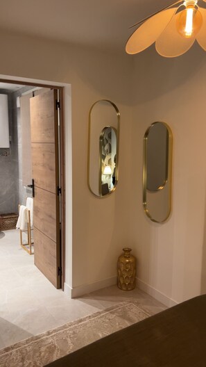 A room with a wooden wardrobe, a mirror, a vase, and a ceiling fan. - Le Petit Rocher Doré: a unique getaway with a view of the Rock. (Pierrelatte)