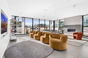 A modern living room with a fireplace, large windows, and a city view. - Bright 2-bed Apartment Near South Melbourne (Melbourne)