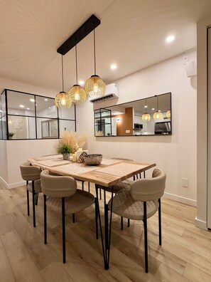 A dining area with a wooden table, six chairs, and hanging pendant lights. - Luxury 2BR • 2.5 Bath Designer Home Retreat (Montréal)