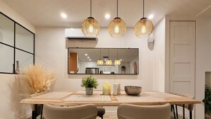A dining area with a wooden table, four chairs, a potted plant, candles, and a bowl. - Luxury 2BR • 2.5 Bath Designer Home Retreat (Montréal)
