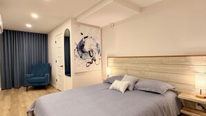 A modern bedroom with a large bed, a blue armchair, and a wall-mounted artwork. - Luxury 2BR • 2.5 Bath Designer Home Retreat (Montréal)