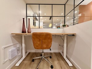 Ein moderner Arbeitsraum mit einem Holztisch, einem braunen Bürostuhl und einem weißen Heizkörper.