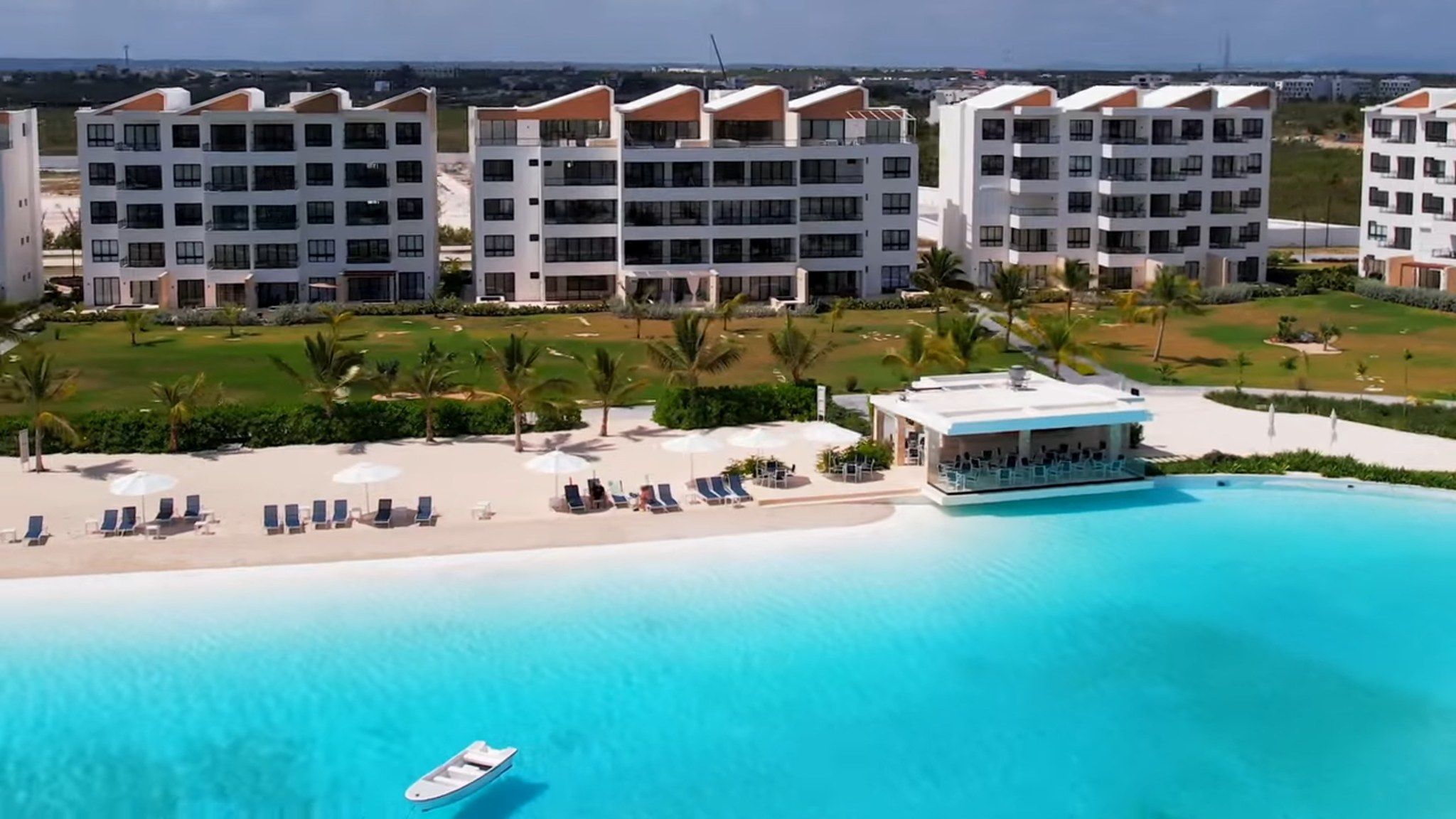 A resort with multiple-story buildings, a beachfront, and a pool area.