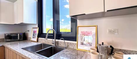 A modern kitchen with granite countertops, stainless steel appliances, a double sink, and framed pictures on the wall.
