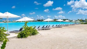 Ein Poolbereich direkt am Strand mit Liegestühlen und Sonnenschirmen.