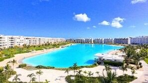 Et resort med en stor swimmingpool, flere hotelbygninger og palmer.