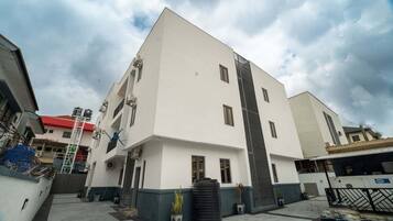 A modern multi-story building with a flat roof, large windows, and a balcony.