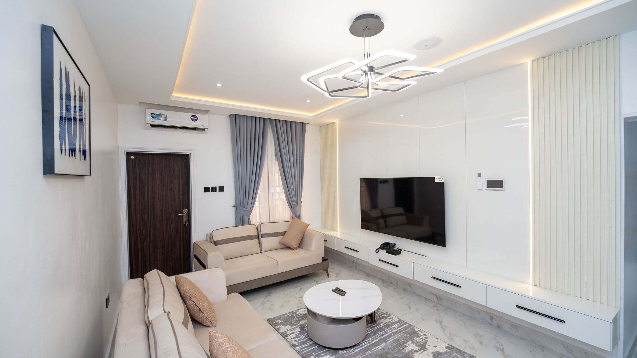 Una sala de estar moderna con sofá, mesa de centro, televisor y armarios empotrados.