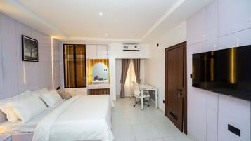 A hotel room with a bed, a desk, a television, and a wardrobe.
