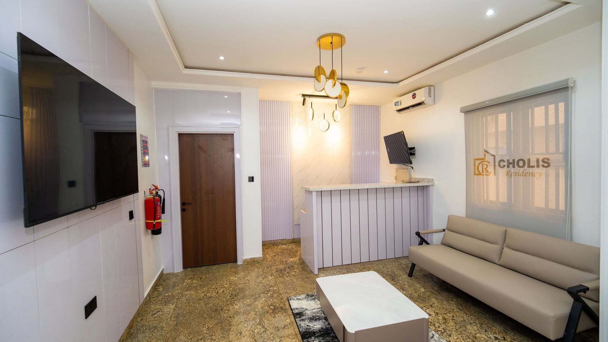 Una sala de estar moderna con un televisor de pantalla plana, un sofá, una mesa de centro, una chimenea y un equipo de aire acondicionado instalado en la pared.