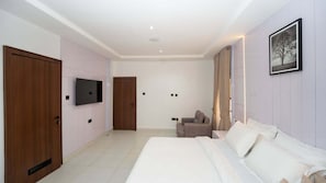 Habitación de hotel con una cama grande, televisor montado en la pared, una puerta y una ventana con cortinas.