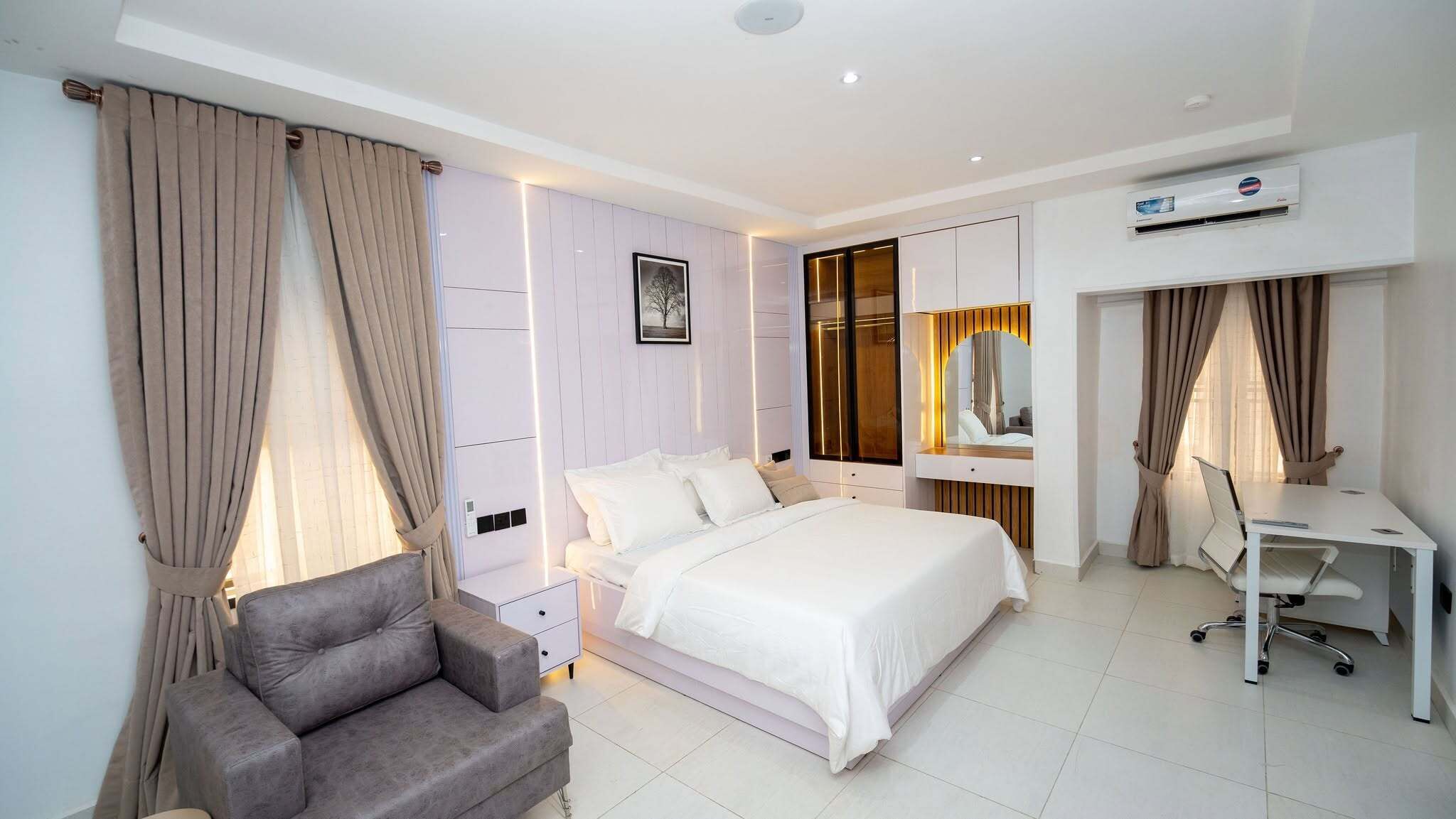 Una habitación de hotel moderna con una cama, un escritorio, una silla y un equipo de aire acondicionado.
