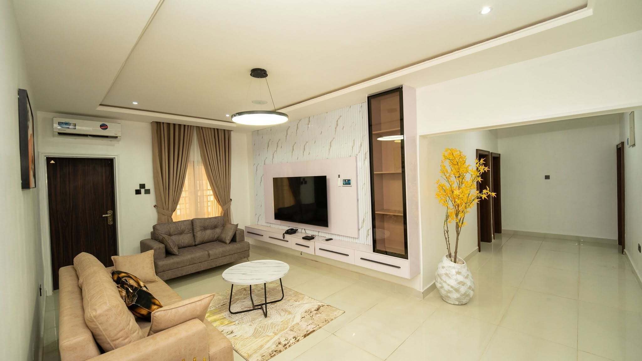 Una sala moderna con sofá, televisor y una planta decorativa.
