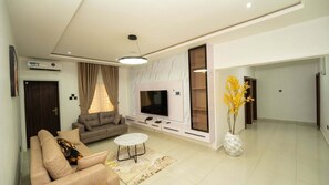 Una sala moderna con sofá, televisor y una planta decorativa.