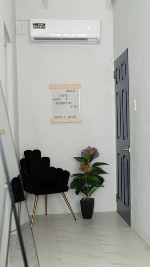 Um corredor com uma cadeira preta, um vaso de planta e uma porta.