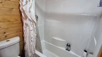 Et badeværelse med et hvidt badekar, et toilet og en bruseforhæng.