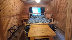 A wooden cabin with a bed, a table, and chairs.