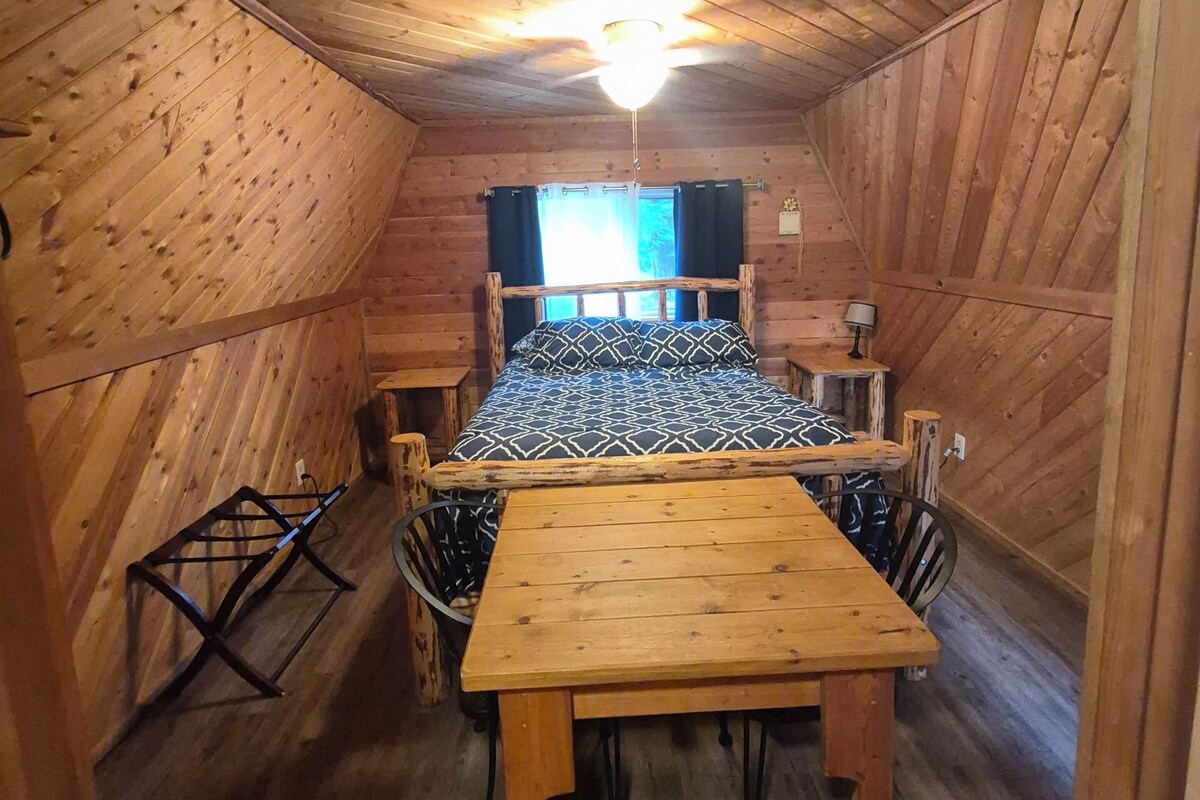 Una cabaña de madera con una cama, una mesa y sillas.