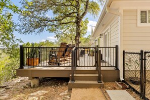 A wooden deck with a metal railing, outdoor furniture, and a potted plant. - Cliffside Lodge + Hill Country Views (Wimberley)