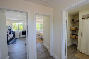 Un dormitorio con cama, escritorio y silla. Se ve una ventana con vistas a árboles.