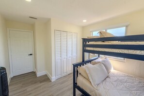 A bunk bed with a window, a door, and a closet in a room with light-colored walls and wooden flooring. - Gateway to the Keys - Private Family Retreat (Homestead)