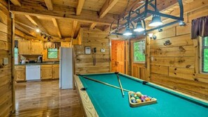 A wooden cabin interior with a pool table, kitchen area, and wooden walls. - Best Location - Walk to Town - Hot Tub - Fireplace (Gatlinburg)
