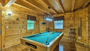 A wooden room with a pool table, two windows with curtains, and a hanging light fixture. - Best Location - Walk to Town - Hot Tub - Fireplace (Gatlinburg)