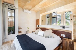 Un dormitorio con una cama grande, cabecera de madera, un espejo y una ventana con cortinas.