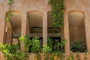 A building facade with three arches and climbing plants. - Villa Romeo | Jungle & Caribbean • Rooftop Pool (Tulum)
