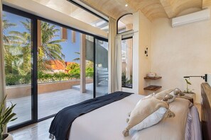 Un dormitorio moderno con una cama grande, vistas a palmeras y un balcón.