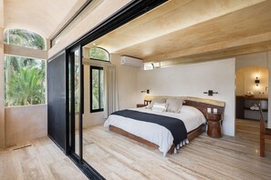 A modern bedroom with a large bed, a sliding glass door leading to a balcony, and a small bedside table. - Villa Romeo | Jungle & Caribbean • Rooftop Pool (Tulum)