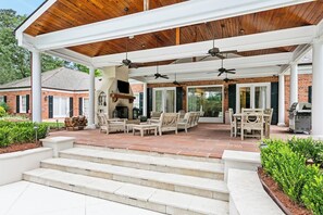 A covered patio with outdoor furniture, a fireplace, and a grill area. - Spacious 7BR Country Retreat w/ Pool, Tennis Court & Private Pond in Folsom, LA (Folsom)