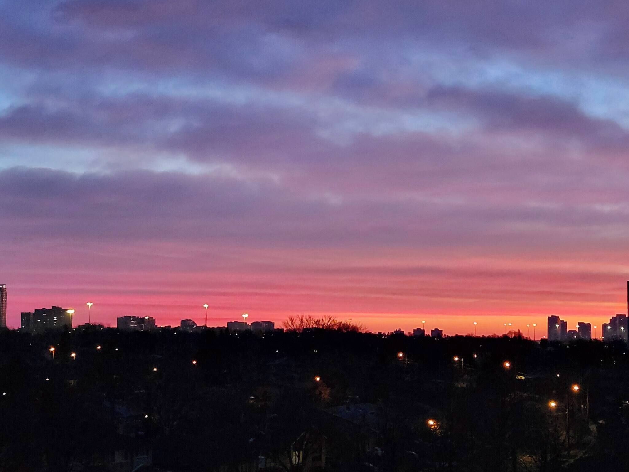 A city skyline at dusk with buildings silhouetted against a colorful sky.