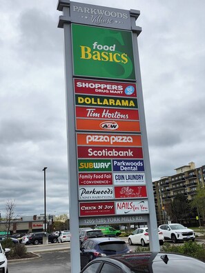 A vertical sign with various business names including food basics, shoppers drug mart, and Tim Hortons.