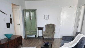 Una sala de estar con sofá, sillón, aparador de madera y una mesita con un cuenco.