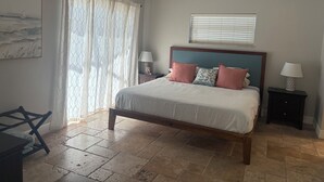 A bedroom with a bed, a ceiling fan, a window with blinds, a nightstand, and a lamp. - Sun-Soaked SW Cape Coral Gulf Access Retreat (Cape Coral)