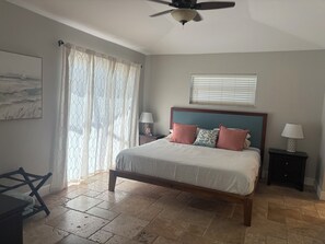 A bedroom with a bed, a ceiling fan, a window with blinds, a nightstand, and a lamp. - Sun-Soaked SW Cape Coral Gulf Access Retreat (Cape Coral)