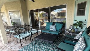 A covered patio area with outdoor furniture, a ceiling fan, and a view through large glass doors. - Sun-Soaked SW Cape Coral Gulf Access Retreat (Cape Coral)