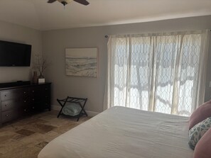 Un dormitorio con cama, cómoda, un cuadro y una ventana con cortinas.