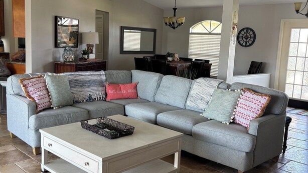 A spacious living room with a sectional sofa, a coffee table, and a ceiling fan. - Sun-Soaked SW Cape Coral Gulf Access Retreat (Cape Coral)