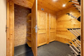 Ein Raum einer Holzsauna mit einer Metall-Ruhebänke, einer Tür mit einer Nummer und einem Lüftungssystem an der Decke.