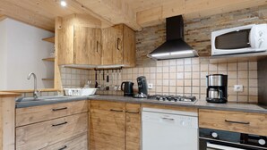 Ett modernt kök med träskåp, en rostfri köksfläkt, en mikrovågsugn och en diskmaskin från Bosch.