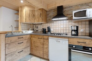 Eine moderne Küche mit Holzausstattung, einer Edelstahl-Dunstabzugshaube, einer Mikrowelle und einem Geschirrspüler von Bosch.
