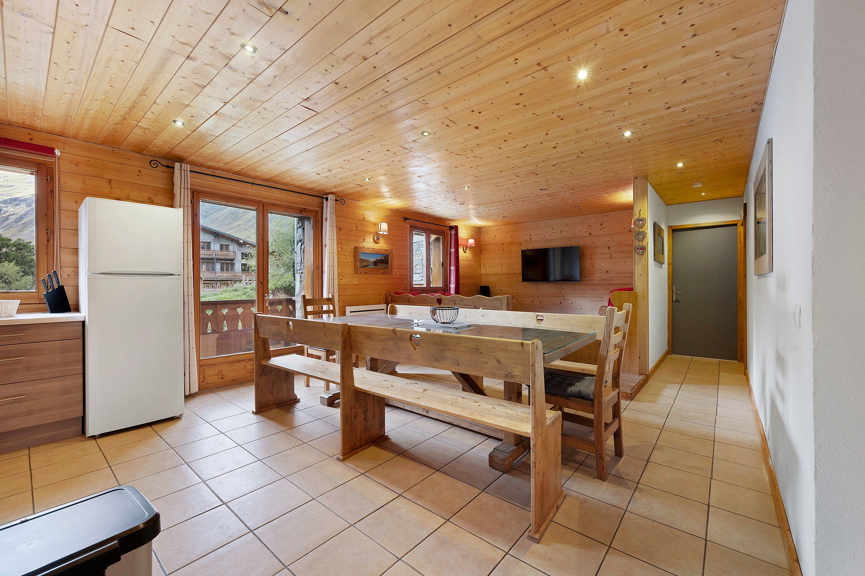 A wooden interior with a kitchen, dining area, and a view of the outside.
